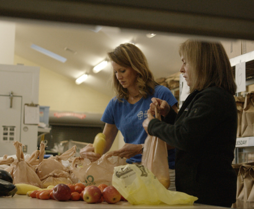 two ladies help package groceries